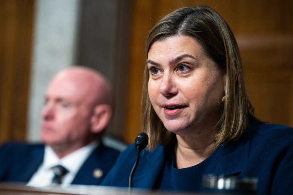 Elissa Slotkin, right, speaks into a microphone. Mark Kelly is out of focus behind her and to her left.