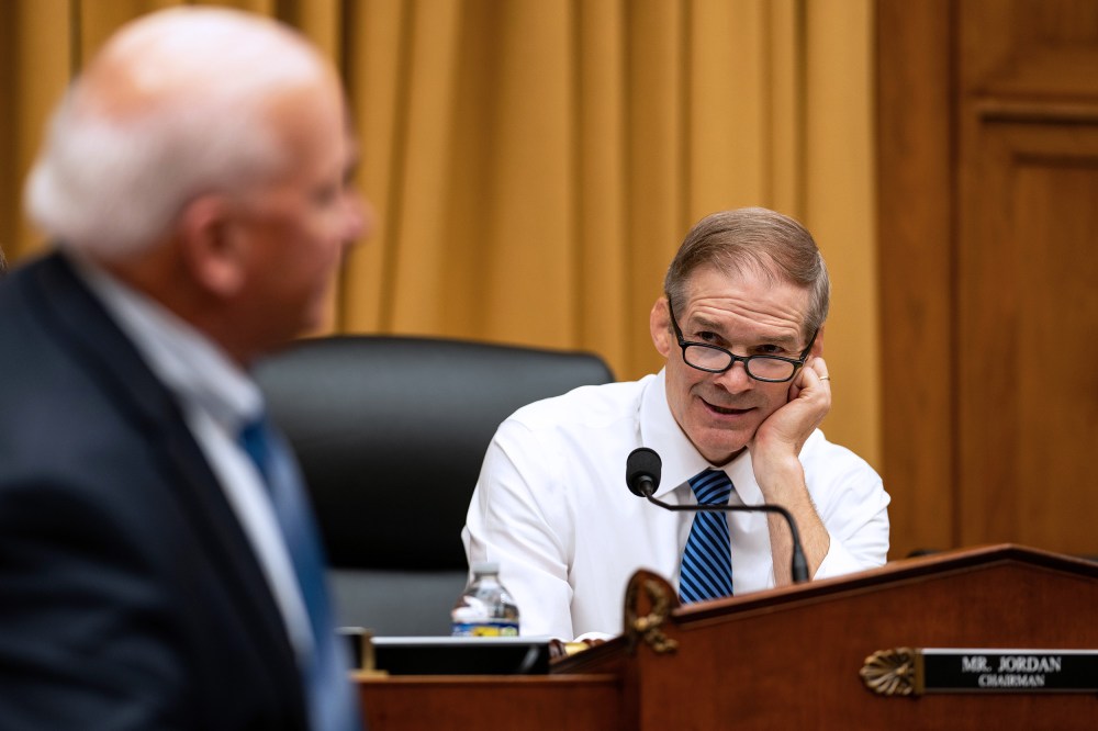 Jim Jordan, right, rests his head on his hand as he talks to a person turned away from the camera.
