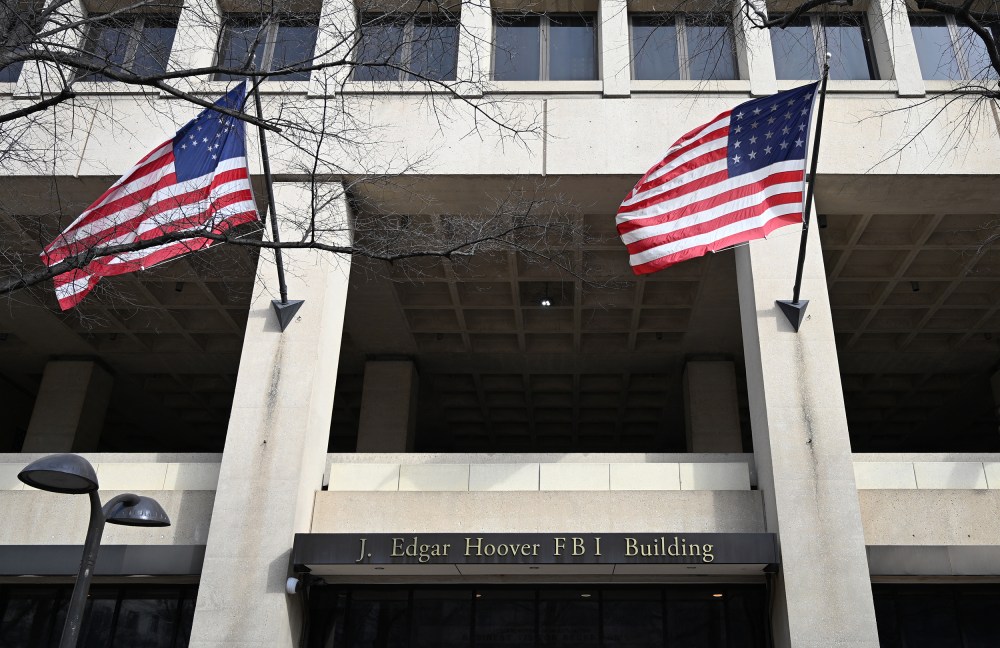 FBI headquarters sign is seen between two American flags.