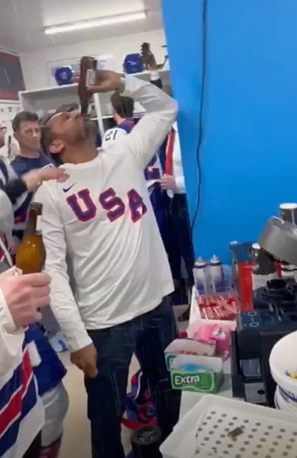 Kash Patel drinks a beer ion front of hockey players.