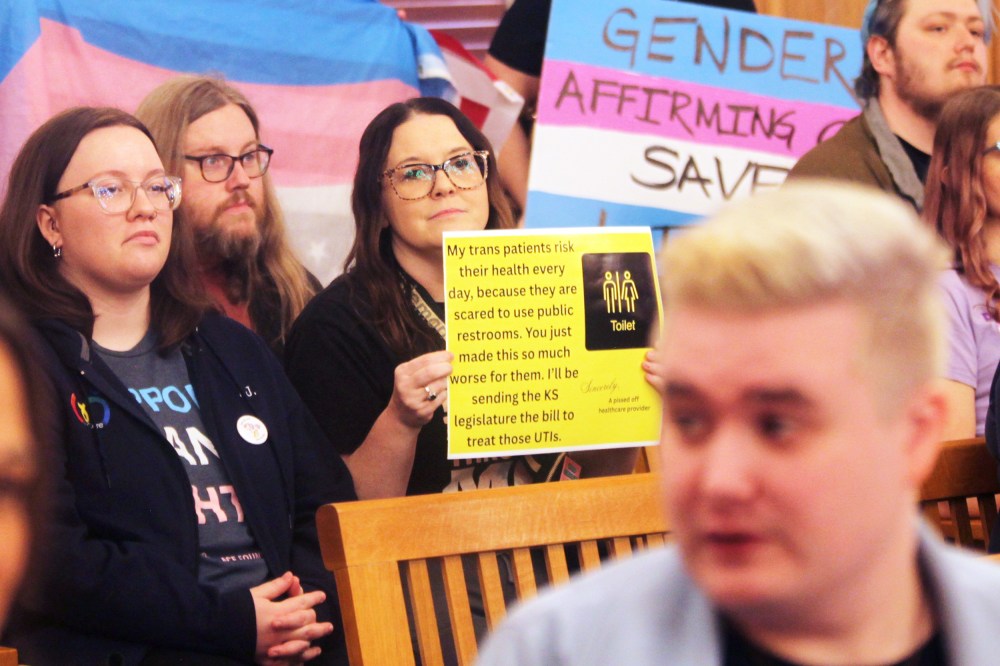 Several people hold up pro-transgender rights signs.
