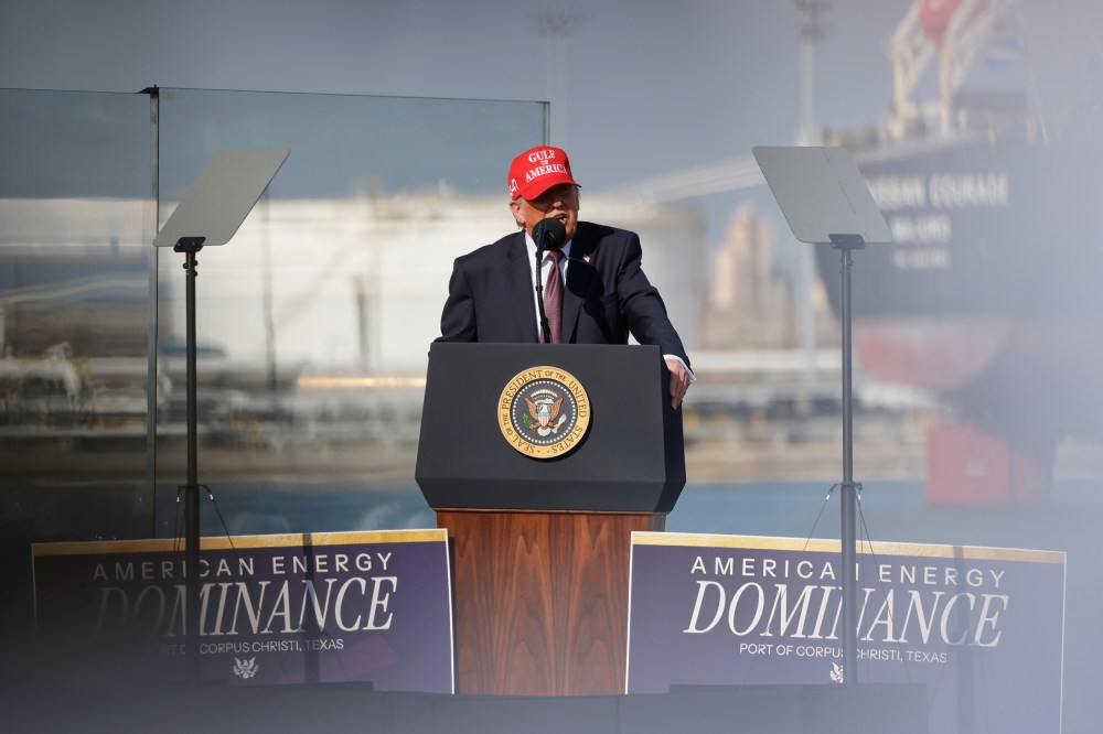 Donald Trump speaks into a microphone at a podium. He's wearing a red hat that says "Gulf of America."