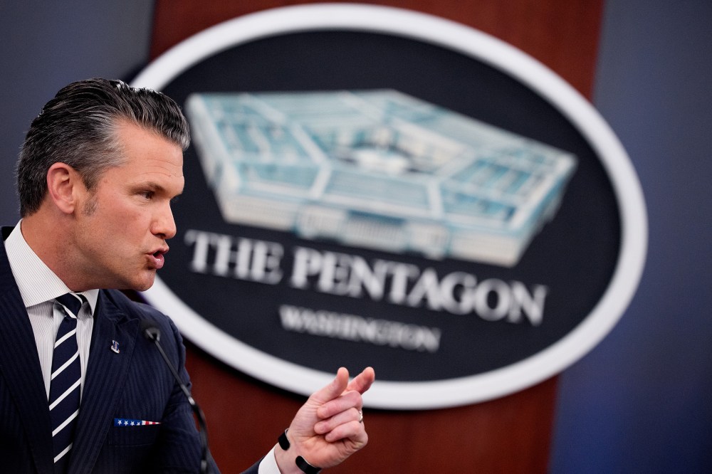 Pete Hegseth speaks in front of a sign for the Pentagon.