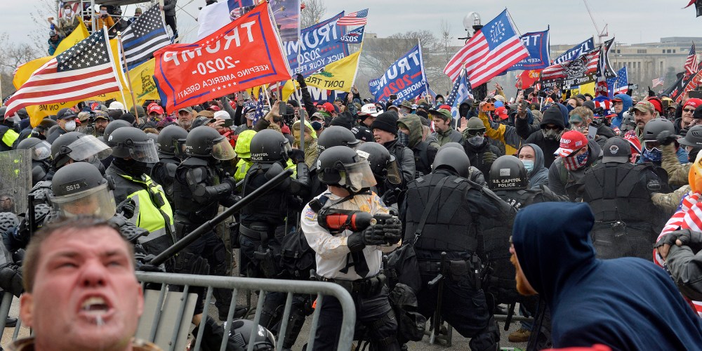A man seen screaming in the foreground as other protestors clash with law enforcement.