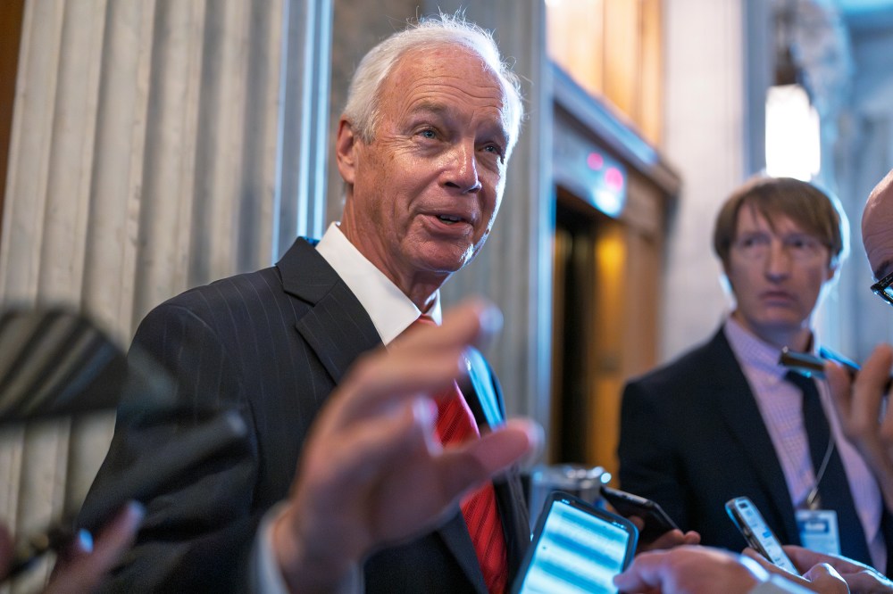 Ron Johnson surrounded by people holding their phones out to him.