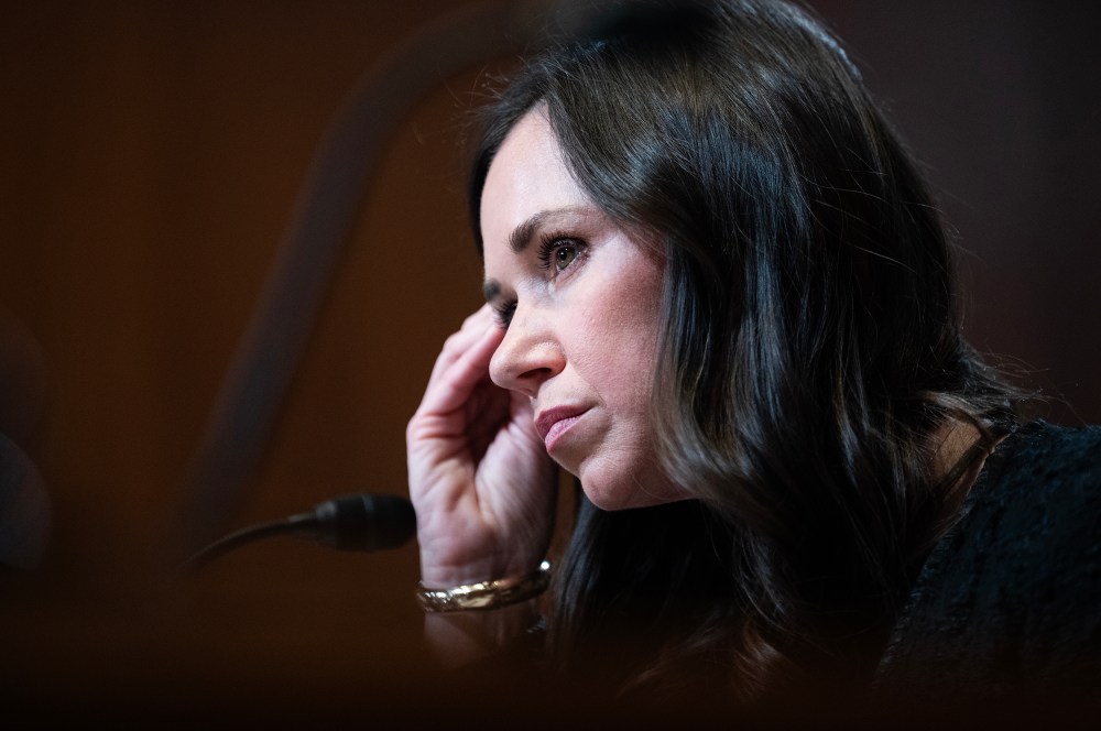 Katie Britt leans her head on her right hand as she looks on.