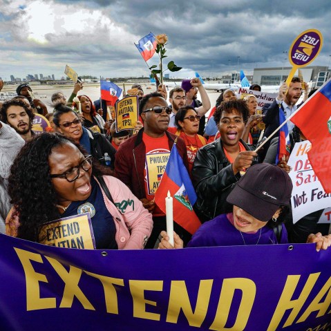 A crowd of people hold Haitian flags and signs calling for an extension of Haitian TPS.