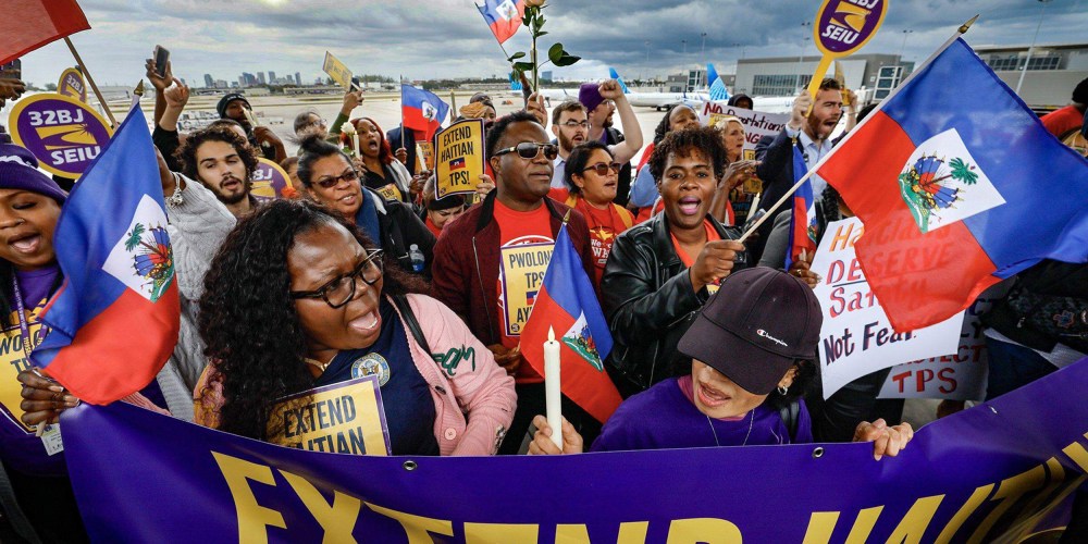 A crowd of people hold Haitian flags and signs calling for an extension of Haitian TPS.