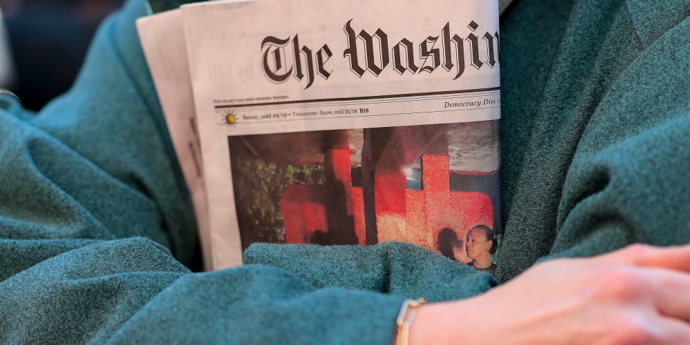 In this close-up shot of crossed arms, a woman holds a copy of The Washington Post tightly.
