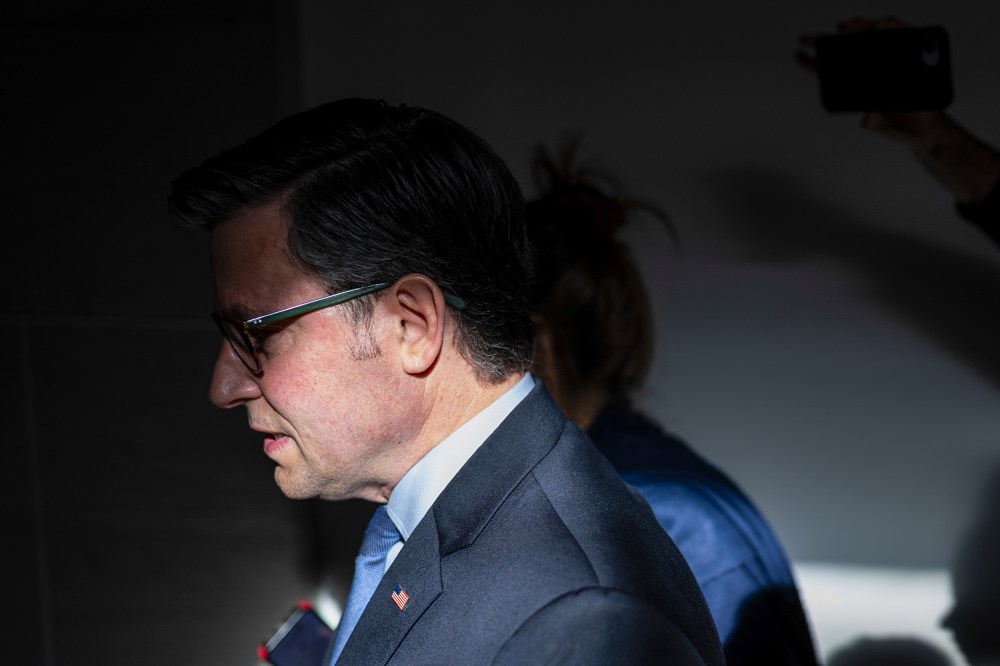 Mike Johnson seen at profile, his face partially obscured in shadow.