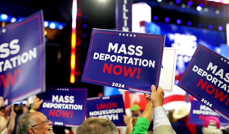 cDelegates hold "Mass Deportations Now" campaign signs during the Republican National Convention (RNC).