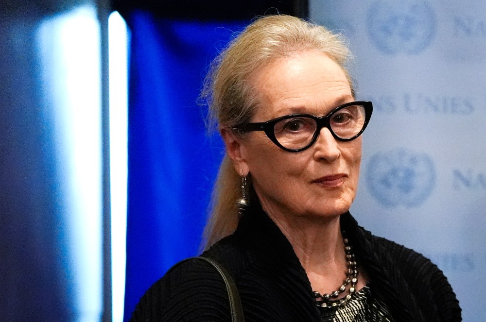 Merly Streep looks on while wearing black framed glasses.