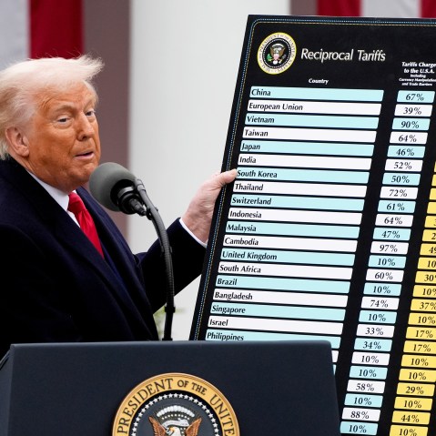 Donald Trump looks toward the audience as he holds a poster.