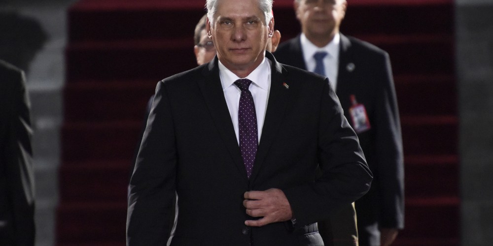 Miguel Díaz-Canel walks toward the camera with his hand on his suit jacket's button.