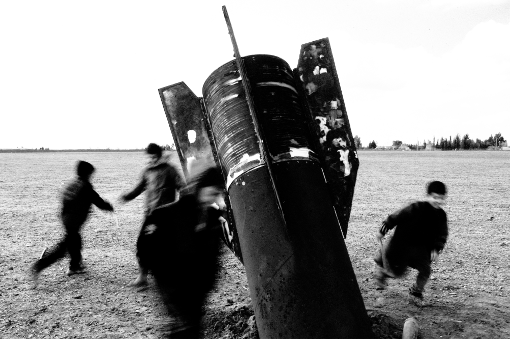 Children play around an unexploded missile that landed in an open field on the outskirts of Qamishli, eastern Syria, on March 5, 2026